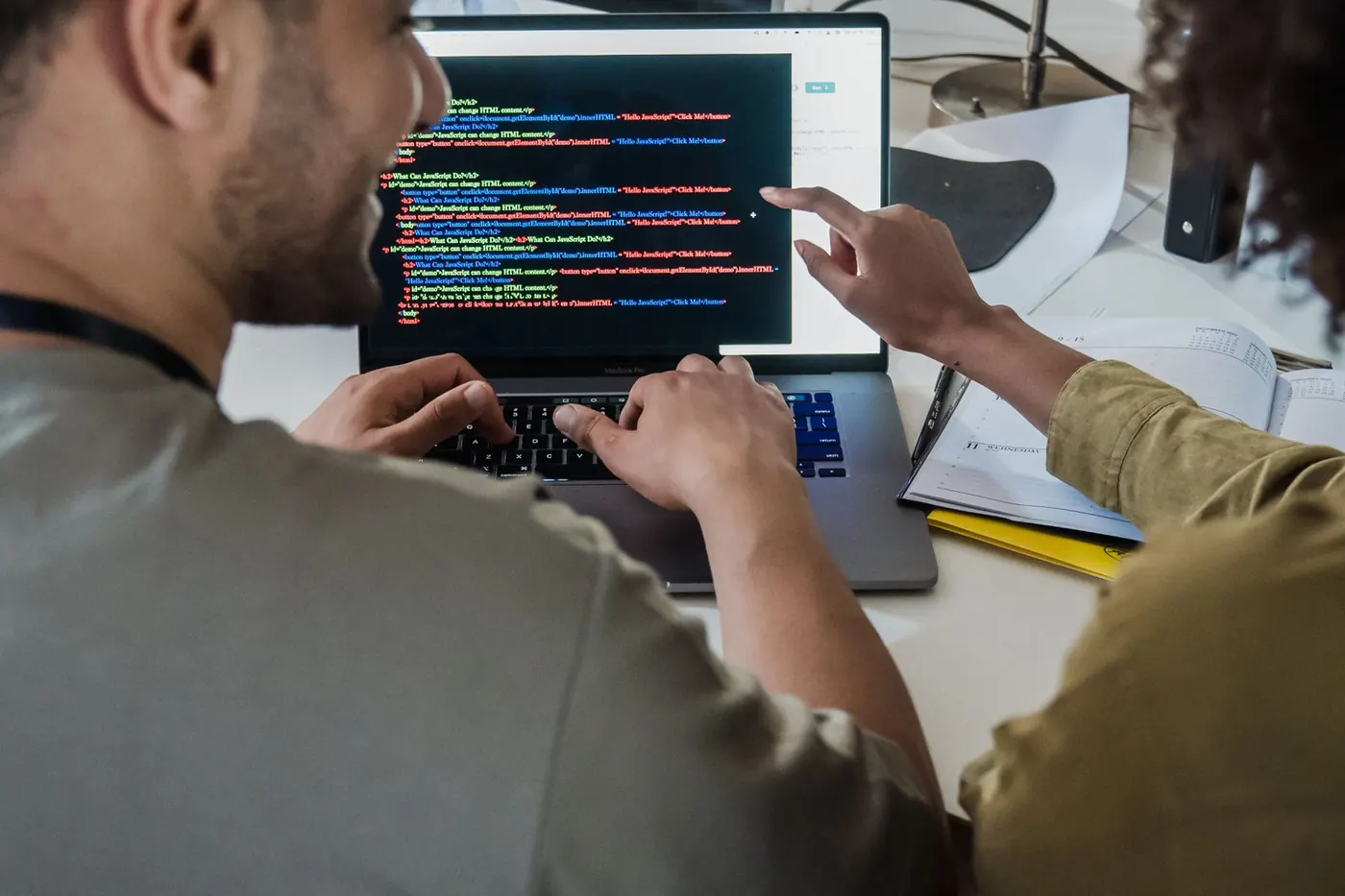 Two engineers discussing code on a laptop